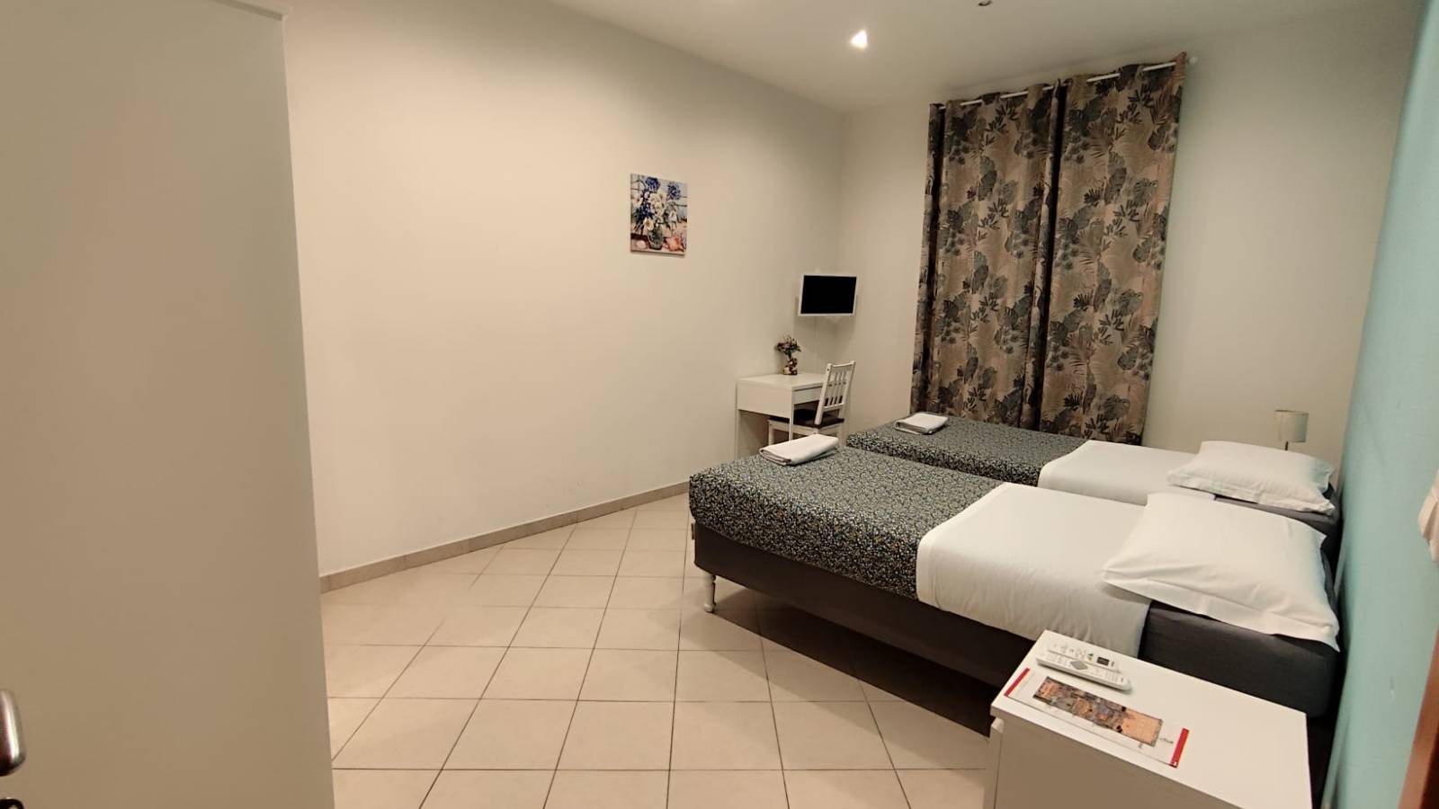 Alt Text: Spacious and bright master bedroom with a queen-size bed, vibrant "full of colour" decor, and air conditioning at Roma Tourist Home, Rome.